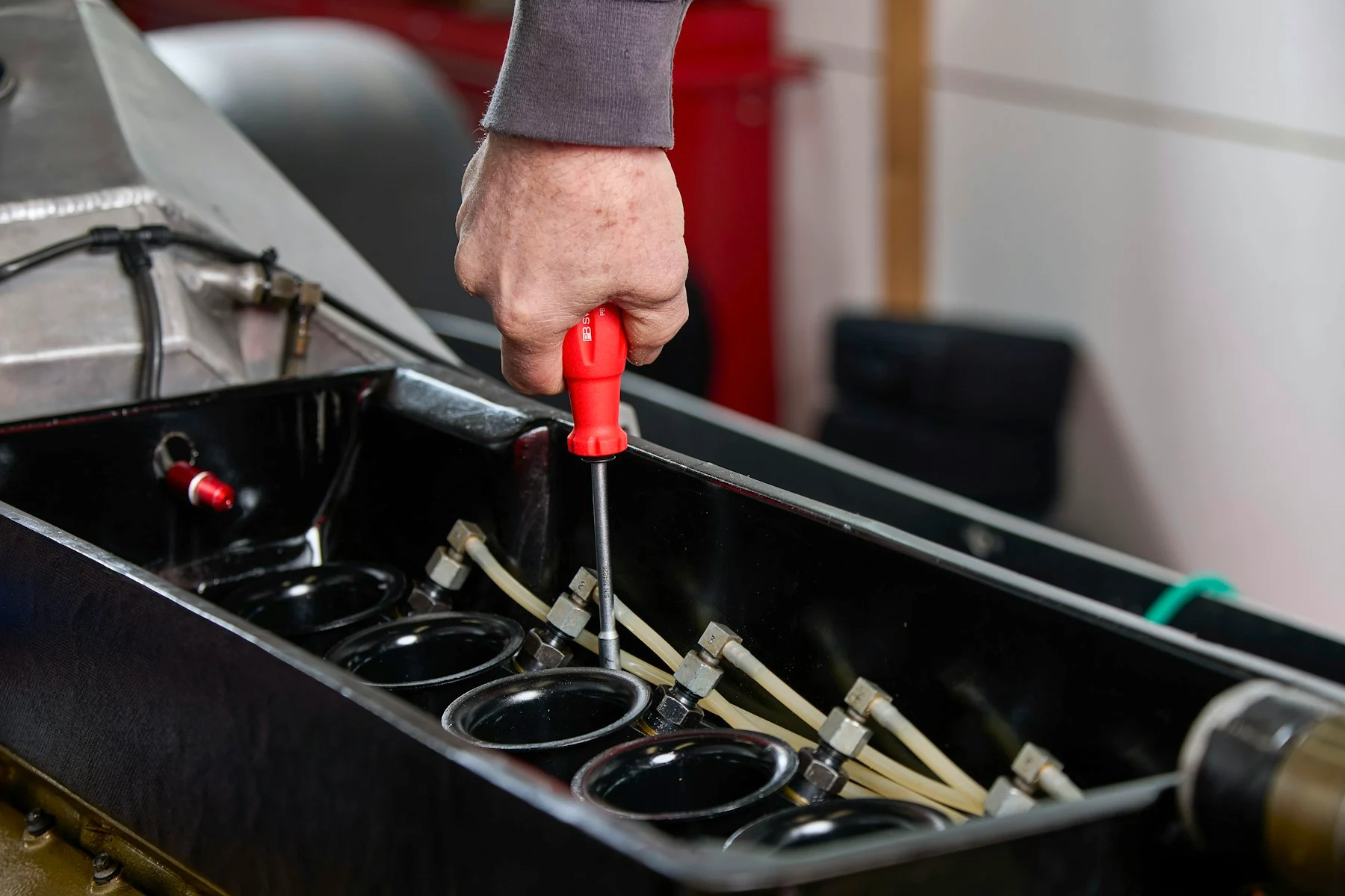 Mechanic using a screwdriver on engine components